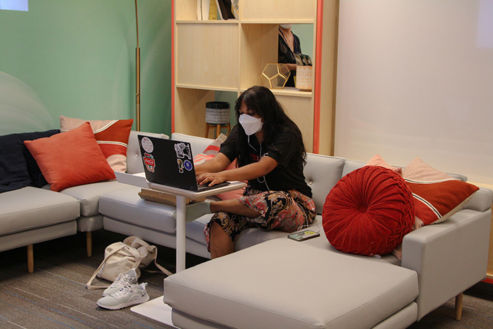 A student wearing a mask studies at a laptop